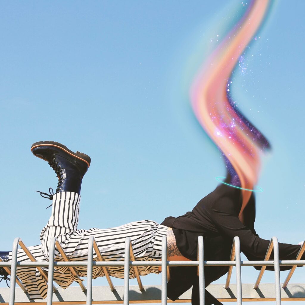 A person on their stomach wearing boots, striped pants and a black shirt. Their head is replaced by a pink and purple ribbon of energy. A blue sky is behind them.