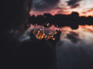 Small lights in a woman's hands at night. Photo by Natalya Letunova on Unsplash