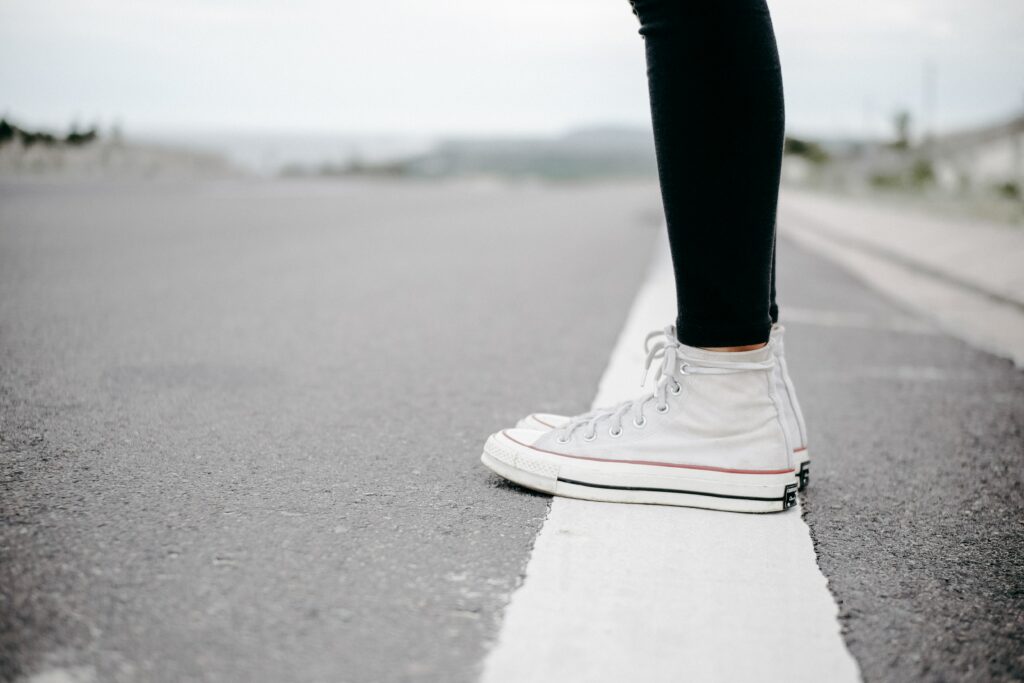 Photo by dương-nhân on Pexels. Person standing in hightops on a white line on a road